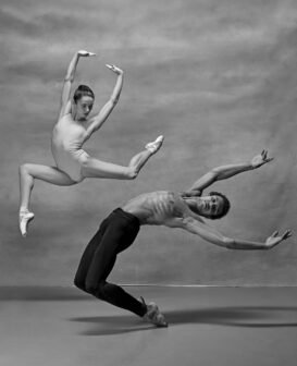 Couple of ballet dancers posing over gray background