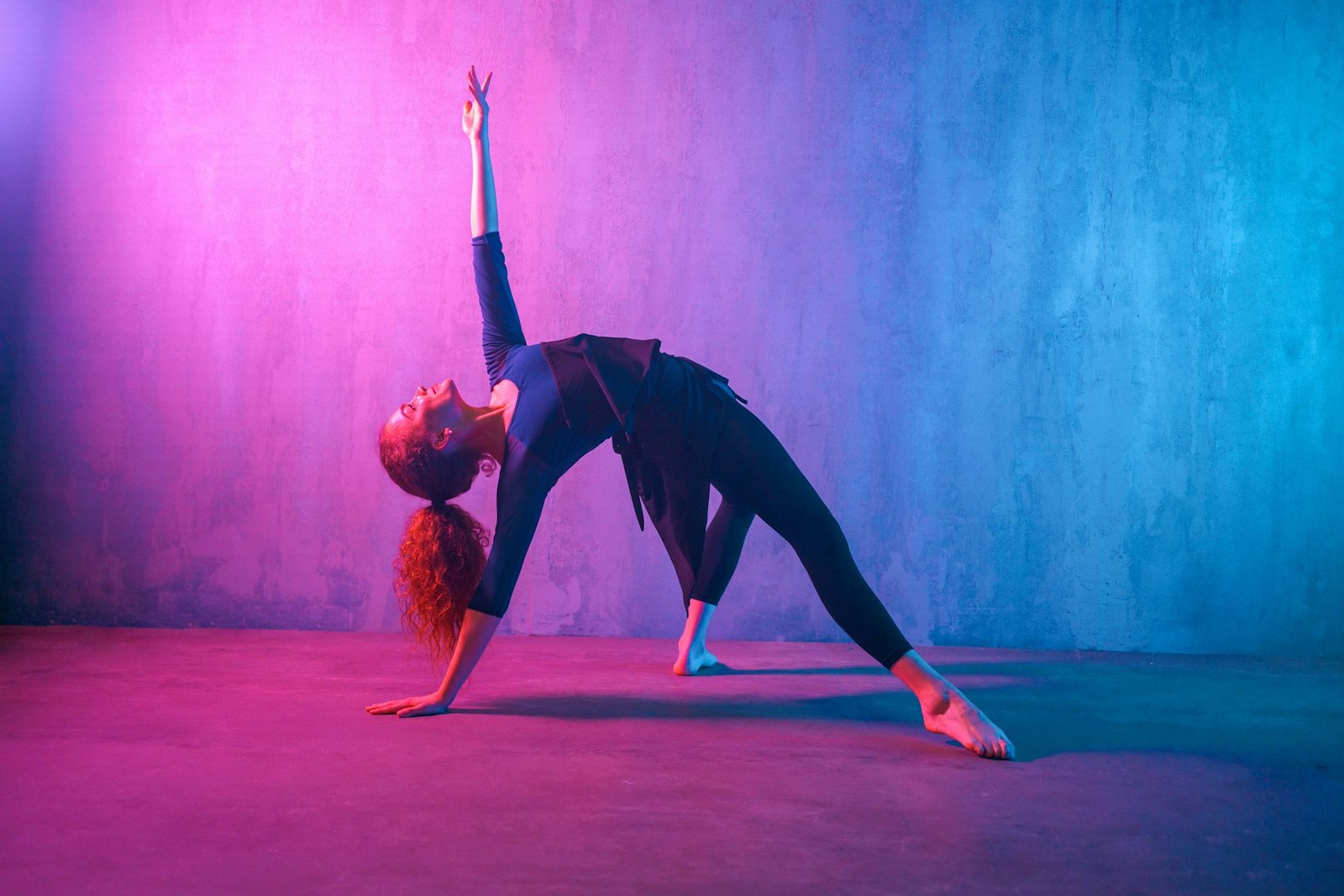 Modern dance girl dancer dancing in neon light doing gymnastic exercises in studio, copy space.